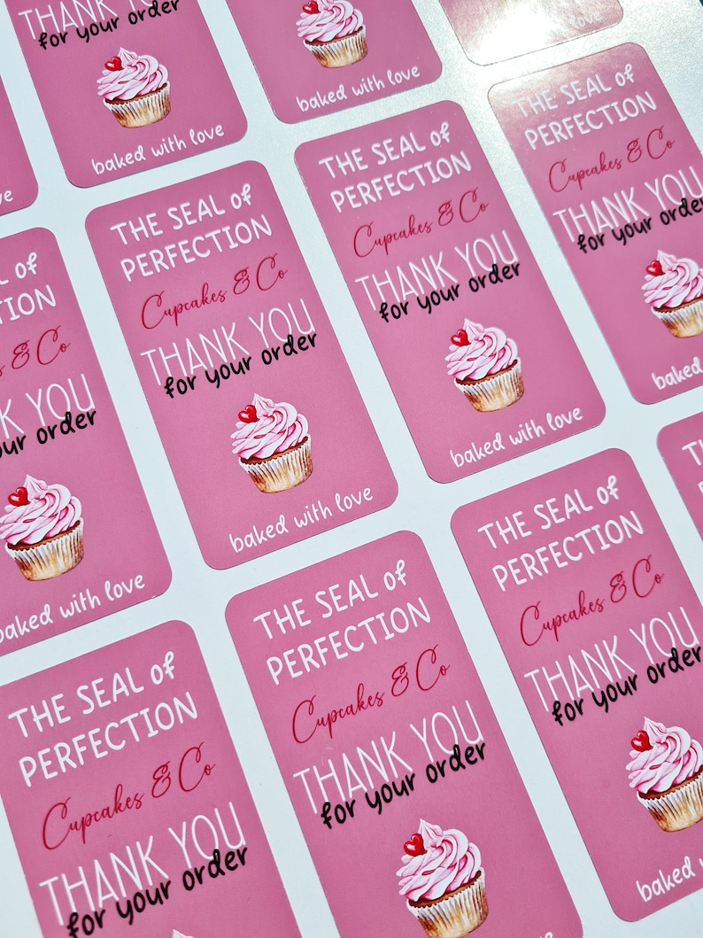 May include: Pink and white cupcake stickers with the text "The Seal of Perfection Cupcakes & Co. Thank You for your order" and "baked with love".