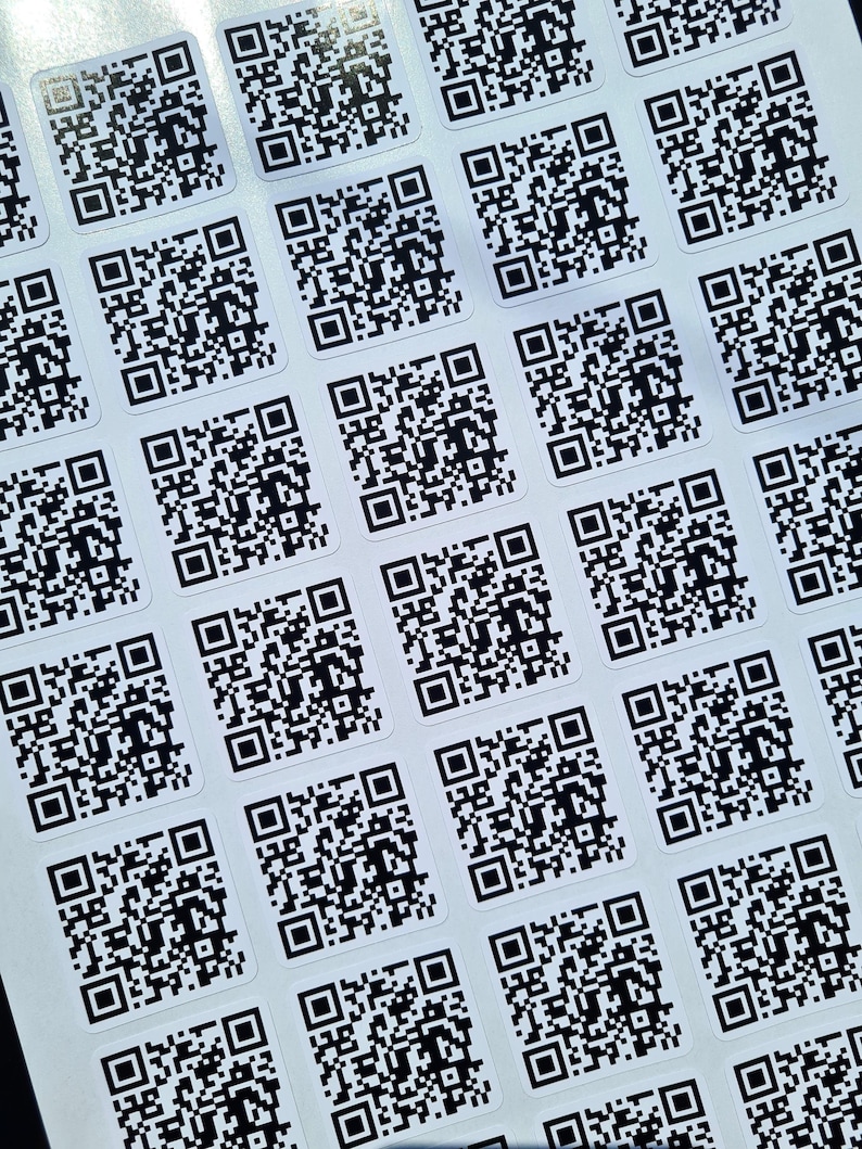 Peut inclure: Une feuille de papier blanche avec plusieurs autocollants de code QR noir et blanc.