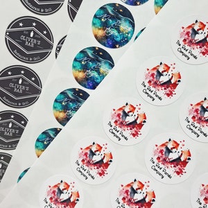 May include: A sheet of white sticker paper with round stickers featuring a watercolor illustration of two red pandas cuddling. The stickers have the text "The Red Panda Company" printed on them.