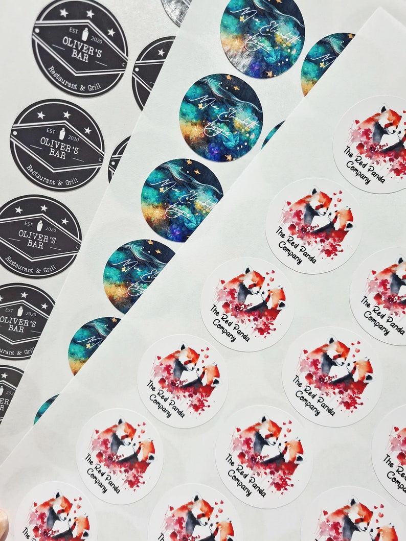 May include: A sheet of white sticker paper with round stickers featuring a watercolor illustration of two red pandas cuddling. The stickers have the text "The Red Panda Company" printed on them.