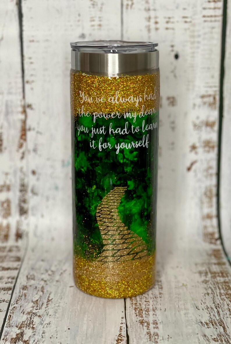 May include: A gold and green glitter tumbler with a yellow brick road design and the quote "You've always had the power my dear you just had to learn it for yourself".
