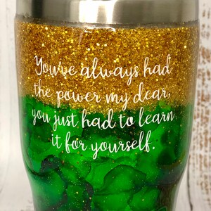 May include: A green and gold glitter tumbler with the quote "You've always had the power my dear, you just had to learn it for yourself."