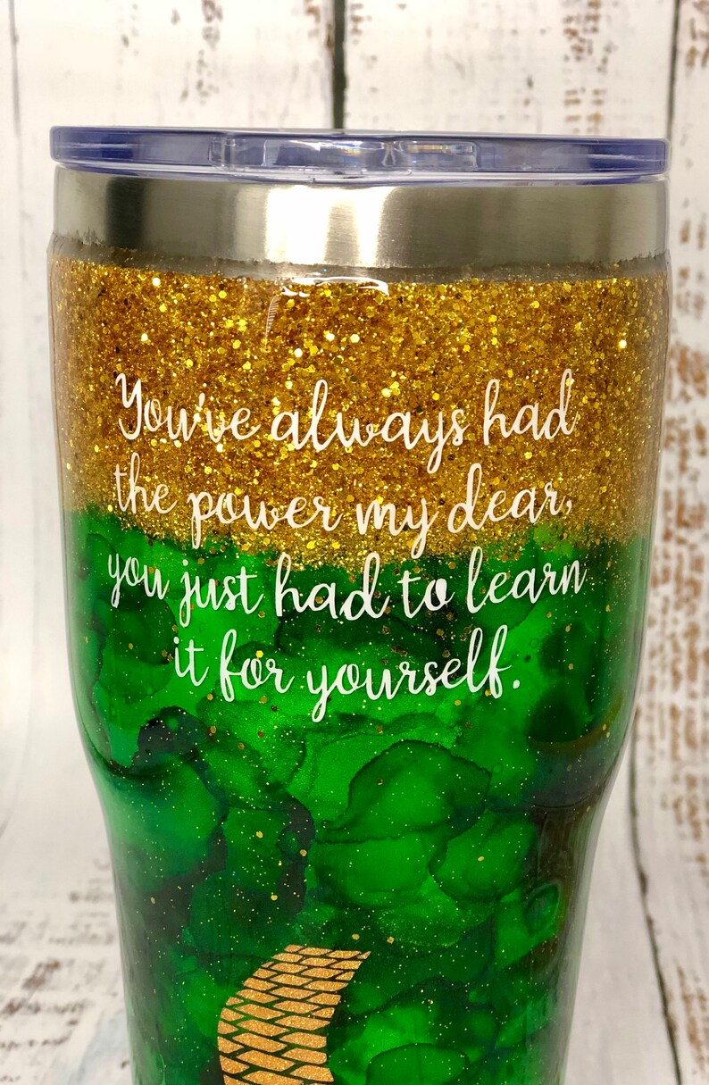 May include: A green and gold glitter tumbler with the quote "You've always had the power my dear, you just had to learn it for yourself."
