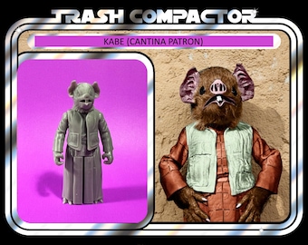 Könnte beinhalten: Vintage "Trash Compactor" Actionfigur mit Kabe, dem Cantina-Gast. Die graue Figur trägt eine Jacke und einen Rock. Die Verpackung enthält den Text "Ages 14 and up" und "Notatoy".