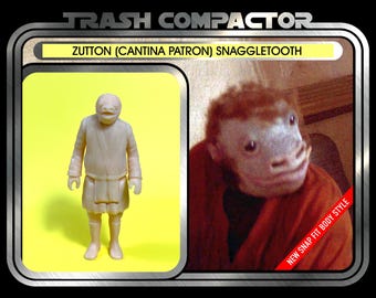 May include: A vintage-style action figure package featuring a beige Zutton (Cantina Patron) Snaggletooth figure. The package includes a photo of the character and text that reads "Trash Compactor" and "New Snap Fit Body Style."