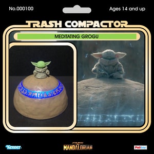Pu&ograve; includere: Un giocattolo "Trash Compactor" di Star Wars con "Meditating Grogu". Il giocattolo ha una base illuminata con dettagli blu e una figura di Grogu sopra. La confezione include il testo "Ages 14 and up", "Kenner", "Star Wars: The Mandalorian" e "Palitoy".