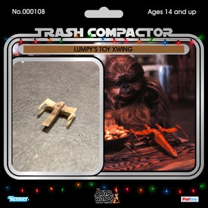 May include: A vintage-style toy package featuring a small, tan X-wing fighter model. The package includes the text "TRASH COMPACTOR" and "LUMPY'S TOY XWING". The image also shows a larger, red X-wing model and a furry character.