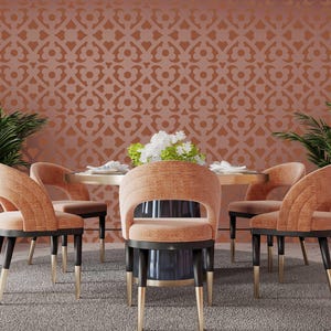 May include: A dining room set featuring a round table and six chairs. The chairs are upholstered in a peachy-orange fabric and have gold-toned legs. The table has a wood top and a gold-toned base. The wall behind the table is covered in patterned wallpaper with a geometric design in shades of brown and orange.