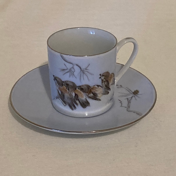 Vintage cup and saucer decorated with birds and pine cones