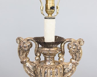 May include: A vintage-style table lamp with a gold-colored finish and ornate details. The lamp features a decorative base with handles and a candle-shaped light bulb. The lamp's height is approximately 18 inches.