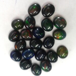 Top-down group of oval opal cabochon pieces, loose black opal gemstone look, dyed Ethiopian opal with green and orange fire