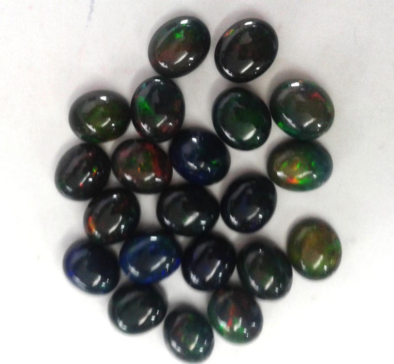 Top-down group of oval opal cabochon pieces, loose black opal gemstone look, dyed Ethiopian opal with green and orange fire