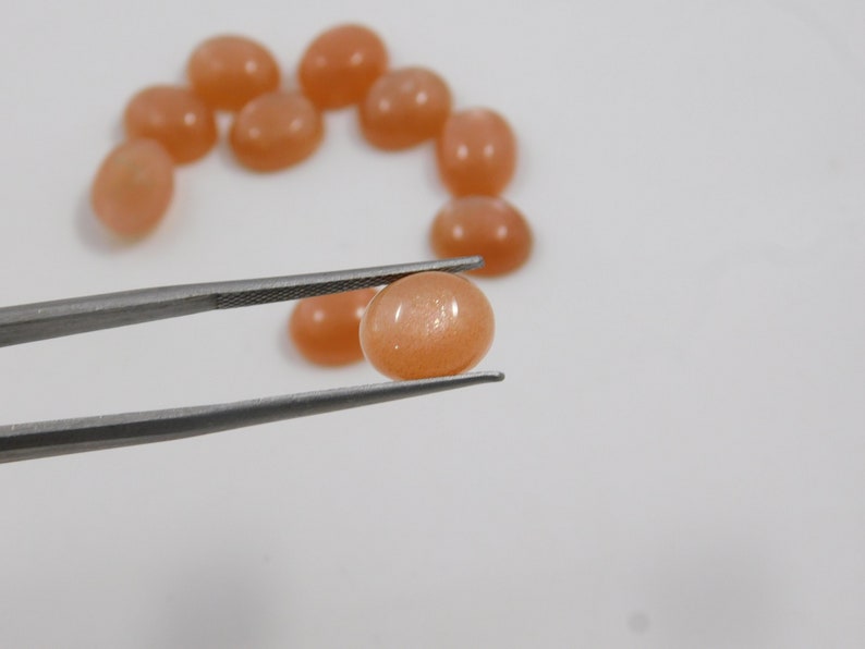 Peach moonstone cabochons, oval-shaped, smooth domed gemstones in peach color; ideal for jewelry making, 5x7–15x20 mm.