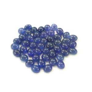 Group of oval blue-violet tanzanite cabochons, natural gemstones with smooth domed tops and flat-back cabochons for jewelry making.