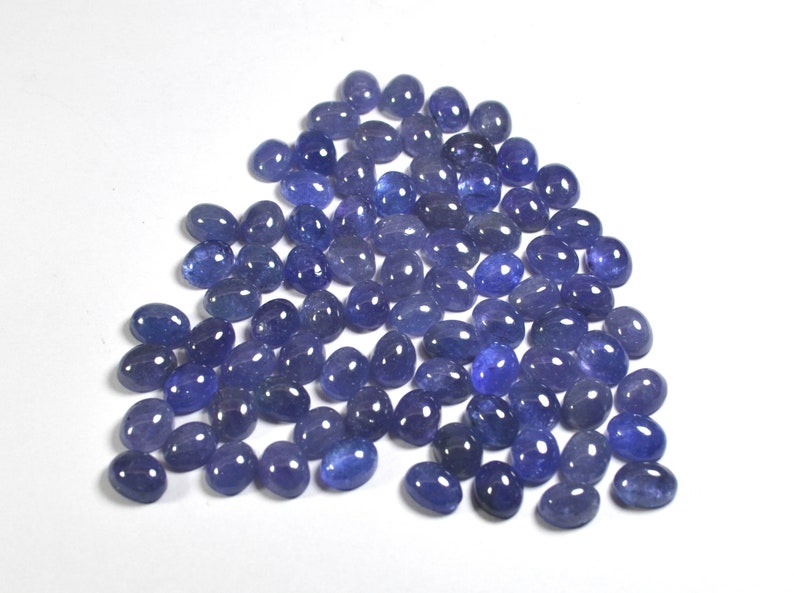 Group of oval blue-violet tanzanite cabochons, natural gemstones with smooth domed tops and flat-back cabochons for jewelry making.