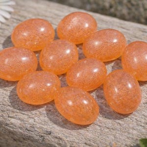 Peach moonstone cabochons, oval-shaped, smooth domed gemstones in peach color; ideal for jewelry making, 5x7–15x20 mm.