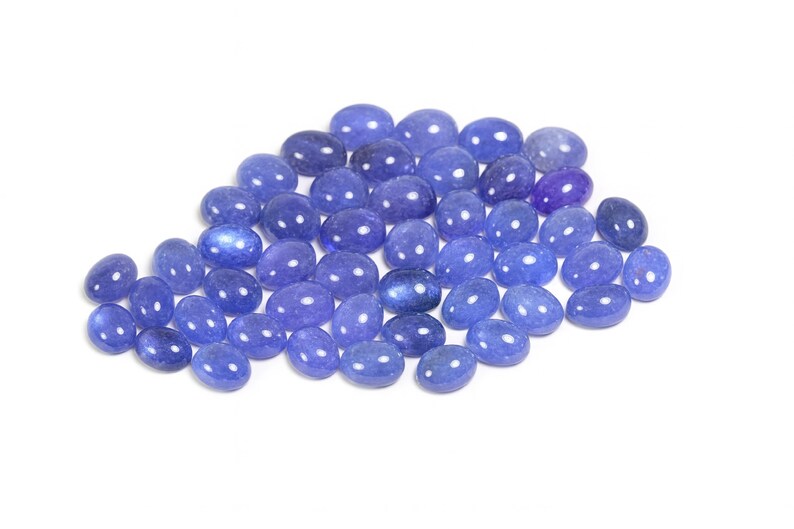Group of oval blue-violet tanzanite cabochons, natural gemstones with smooth domed tops and flat-back cabochons for jewelry making.