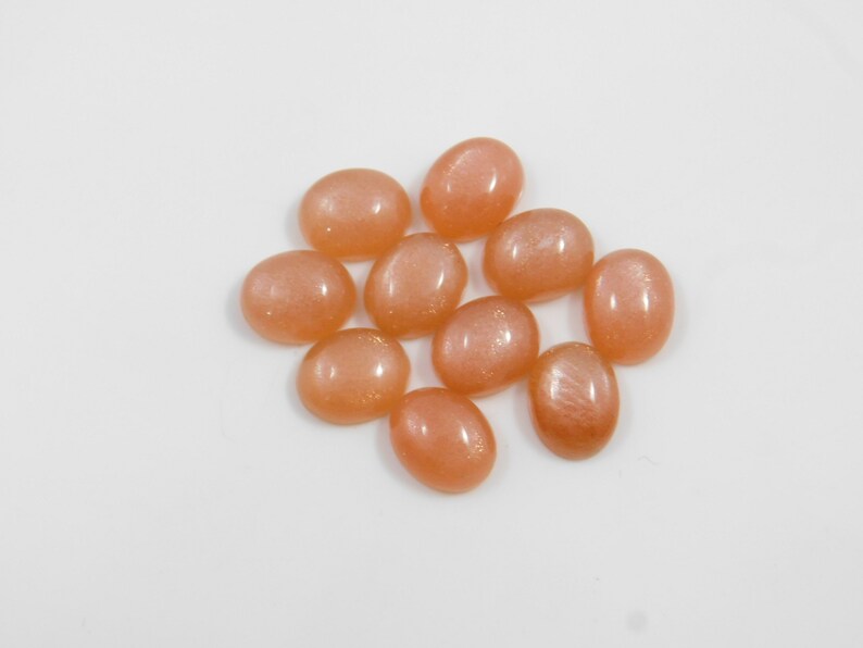 Peach moonstone cabochons, oval-shaped, smooth domed gemstones in peach color; ideal for jewelry making, 5x7–15x20 mm.