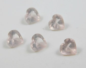 May include: Five pink heart-shaped gemstones. The gemstones are clear and have a slight pink hue.