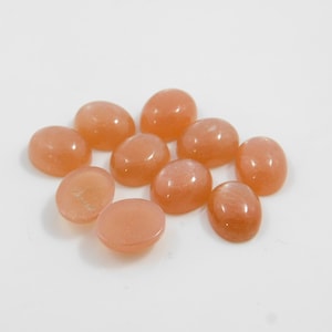 Peach moonstone cabochons, oval-shaped, smooth domed gemstones in peach color; ideal for jewelry making, 5x7–15x20 mm.