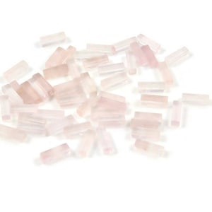 May include: A pile of small, pale pink, rectangular-shaped gemstones. The gemstones are smooth and polished.