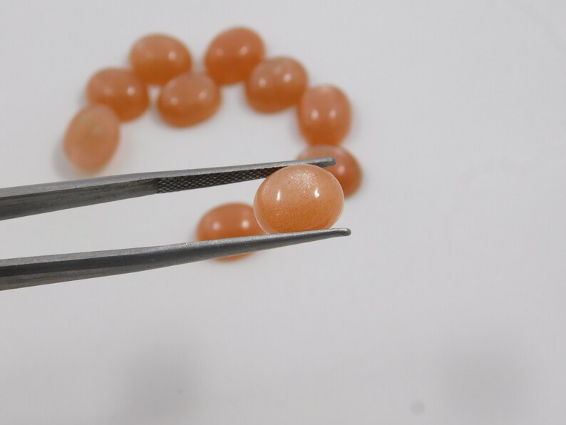 Peach moonstone cabochons, oval-shaped, smooth domed gemstones in peach color; ideal for jewelry making, 5x7–15x20 mm.
