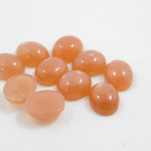 Peach moonstone cabochons, oval-shaped, smooth domed gemstones in peach color; ideal for jewelry making, 5x7–15x20 mm.