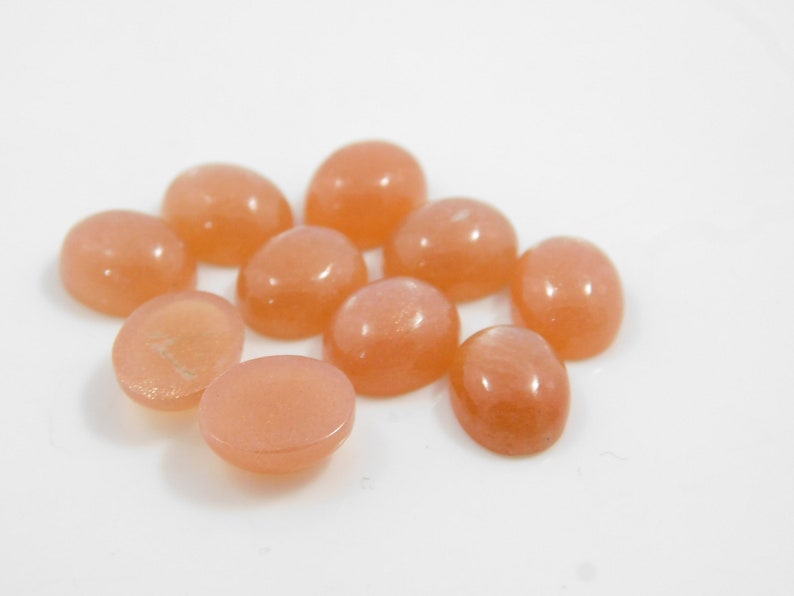 Peach moonstone cabochons, oval-shaped, smooth domed gemstones in peach color; ideal for jewelry making, 5x7–15x20 mm.