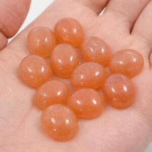 Peach moonstone cabochons, oval-shaped, smooth domed gemstones in peach color; ideal for jewelry making, 5x7–15x20 mm.