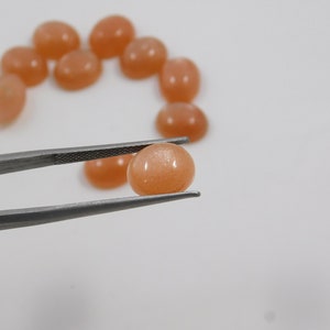 Peach moonstone cabochons, oval-shaped, smooth domed gemstones in peach color; ideal for jewelry making, 5x7–15x20 mm.