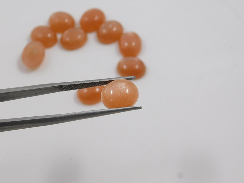 Peach moonstone cabochons, oval-shaped, smooth domed gemstones in peach color; ideal for jewelry making, 5x7–15x20 mm.