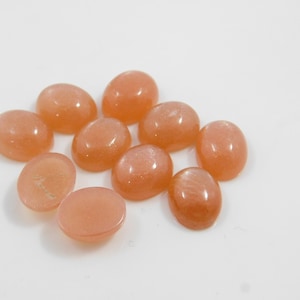 Peach moonstone cabochons, oval-shaped, smooth domed gemstones in peach color; ideal for jewelry making, 5x7–15x20 mm.