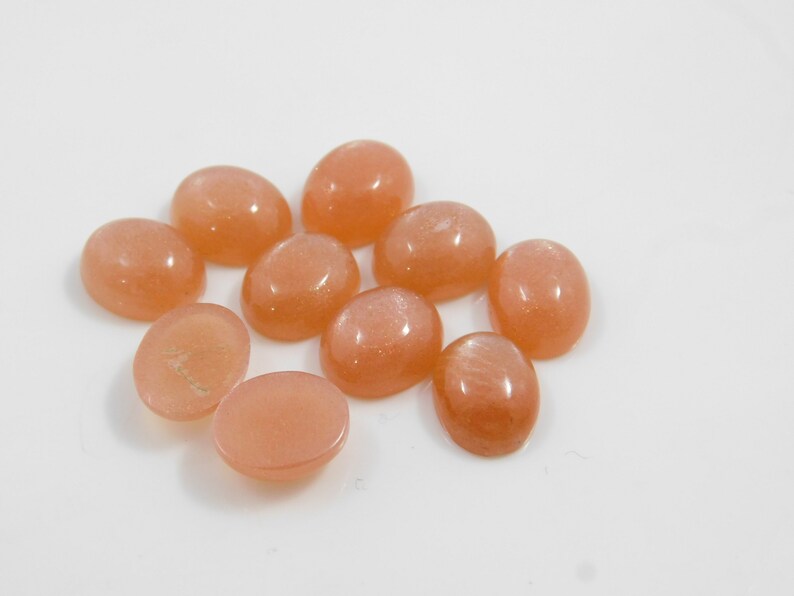 Peach moonstone cabochons, oval-shaped, smooth domed gemstones in peach color; ideal for jewelry making, 5x7–15x20 mm.