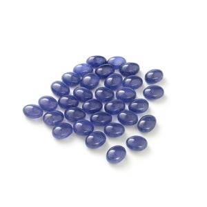 Group of oval blue-violet tanzanite cabochons, natural gemstones with smooth domed tops and flat-back cabochons for jewelry making.