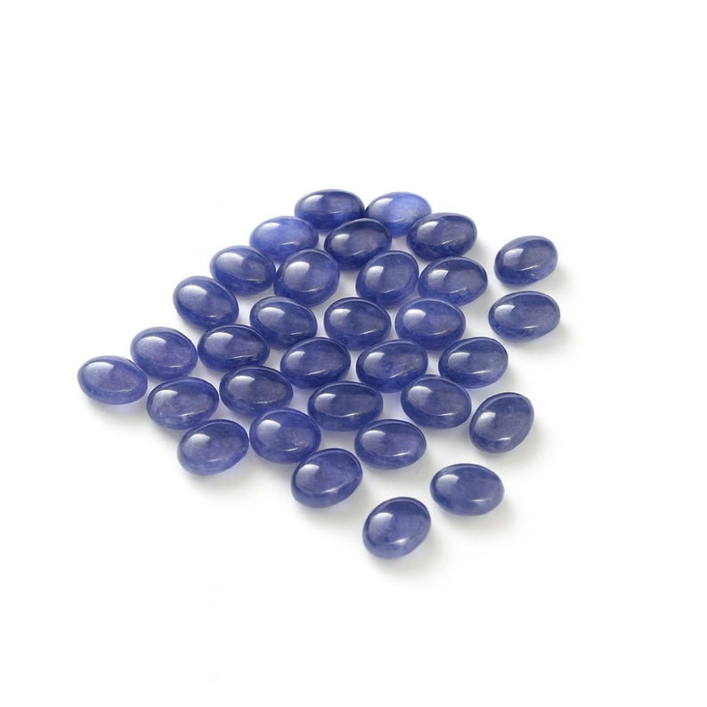 Group of oval blue-violet tanzanite cabochons, natural gemstones with smooth domed tops and flat-back cabochons for jewelry making.