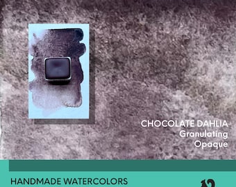 May include: A square watercolor paint pan in a dark brown shade, displayed on a light blue paper swatch with a matching dark brown paint wash. The text reads CHOCOLATE DAHLIA Granulating Opaque, HANDMADE WATERCOLORS Artist Grade Hand Poured.