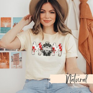Baseball Shirt features distressed font spelling the word Mom and a Catcher's mask in place of the "o" in Mom.