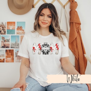 Baseball Shirt features distressed font spelling the word Mom and a Catcher's mask in place of the "o" in Mom.