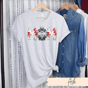 Baseball Shirt features distressed font spelling the word Mom and a Catcher's mask in place of the "o" in Mom.