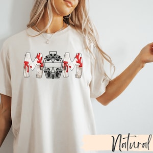 Baseball Shirt features distressed font spelling the word Mom and a Catcher's mask in place of the "o" in Mom.