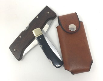 May include: A brown leather sheath with a snap closure holds a folding pocket knife with a wooden handle and a black blade.