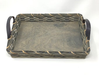 May include: A gray woven tray with leather handles. The tray has a wood bottom and is perfect for serving or displaying items.