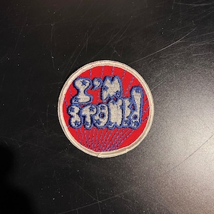 May include: A red and white embroidered patch with the text "I'm strong" in white with blue outlines.
