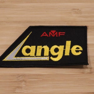 May include: Black embroidered patch with a yellow "Langle" logo and a red "AMF" logo. The patch has a white angled line.