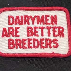May include: Red embroidered patch with white background and the text "Dairymen Are Better Breeders".