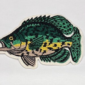May include: Embroidered patch of a green and yellow fish with a white background.