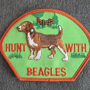 May include: Green and orange embroidered patch with a beagle dog standing in a field. The text "I HUNT WITH BEAGLES" is embroidered in orange.