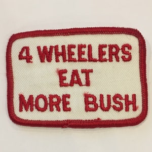 May include: Red embroidered patch with white background. The patch reads "4 Wheelers Eat More Bush".