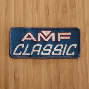 May include: Blue embroidered patch with white stitching that reads "AMF CLASSIC" in all caps. The "M" in AMF has a red triangle above it.