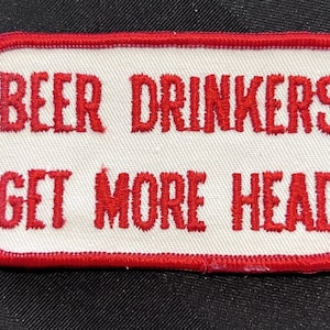 May include: Red embroidered patch with a white background. The patch says "Beer Drinkers Get More Head".